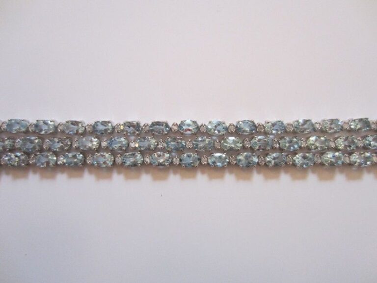 BRACELET articulé en or gris 14 carats (585 millièmes) composé de trois rangs d'aigues-marines de forme ovale alternées de diamants taille brillan