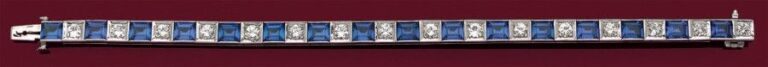 BRACELET articulé en or gris 14 carats (585 millièmes) serti d'un alignement de pierres bleues rectangulaires alternées de diamants taille brillan