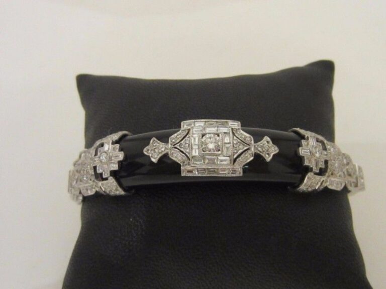 BRACELET articulé en or gris (750 millièmes) ajouré à motifs géométriques serti d’onyx bombé surmonté et épaulé de diamants baguettes et taille brillan