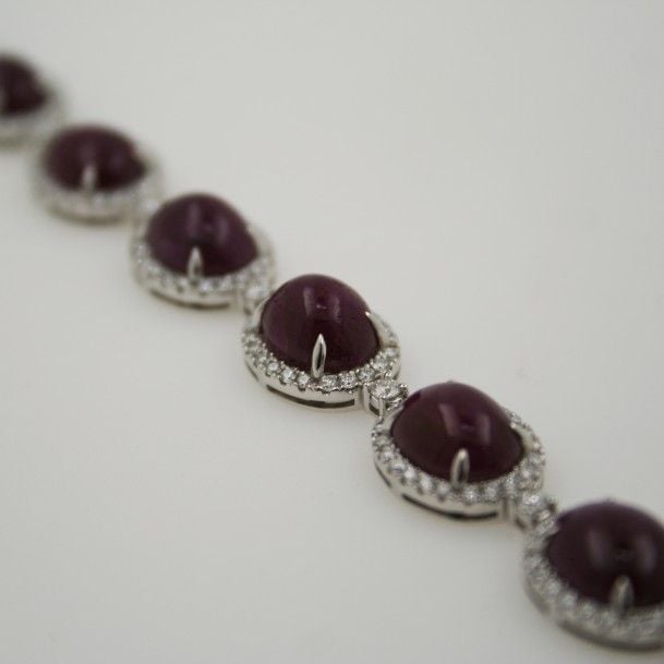 BRACELET articulé en or gris (750 millièmes) serti de dix rubis ovales cabochons entourés de diamants taille brillan