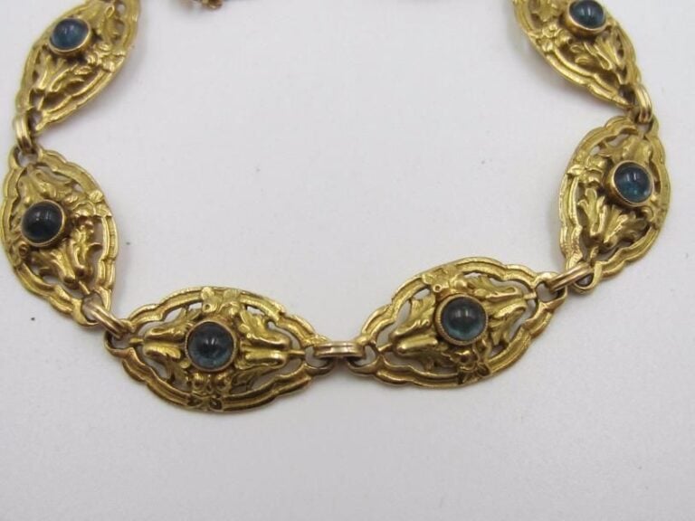 BRACELET articulé en or jaune (750 millièmes) ajouré à motifs ovales ciselés ponctués de pierres de couleur bleue cabochon