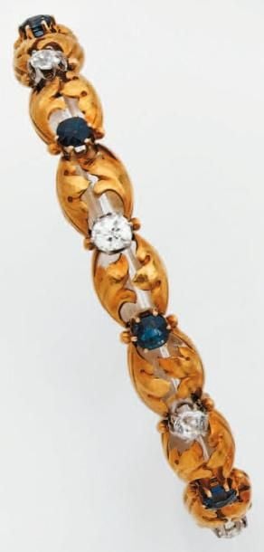 BRACELET articulé en platine et or jaune ajouré, à motifs de volutes serti de diamants taille ancienne et saphirs alterné