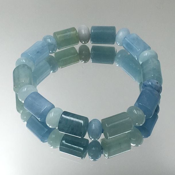 BRACELET composé de perles d'aigues-marines de forme bouton et cylindrique, enfilées sur élastiqu