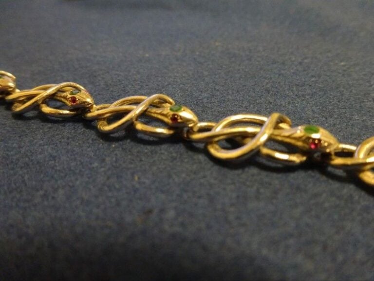 BRACELET en or blanc 18K (750°/00) à maillons articulés en forme de serpents sertis d'émeraudes, en