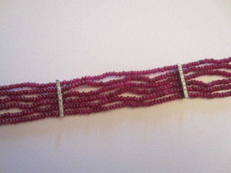 BRACELET en or gris 14 carats (585 millièmes) composé de six rangs de petits perles de rubis facettés rehaussés de diamants taille brillan