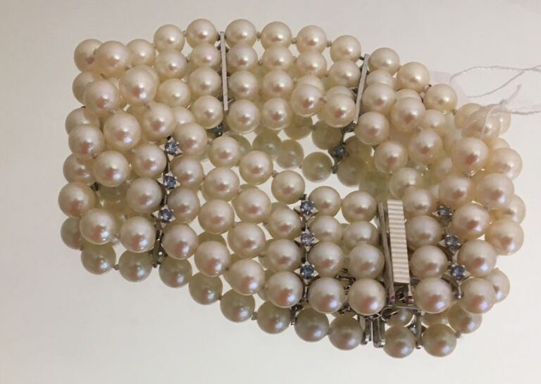 BRACELET en or gris (750 millièmes) guilloché, composé de quatre rangs de perles de culture blanches retenus par des barrettes serties de petites aigues-marine