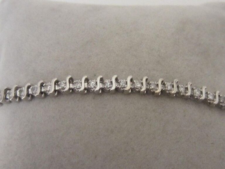 BRACELET en or gris (750 millièmes) serti d'une ligne de 49 petits diamants taille brillant séparés par des motifs sinueu