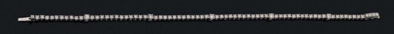 BRACELET fin articulé en or gris (750 millièmes) serti d'un alignement de diamants taille brillant, dont cinq plus important