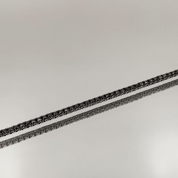 •BRACELET fin en or noirci (750‰) serti d'un alignement de noir