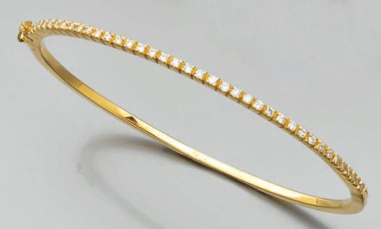 BRACELET fin rigide ouvrant en or jaune partiellement serti d'un alignement de diamants taille brillan