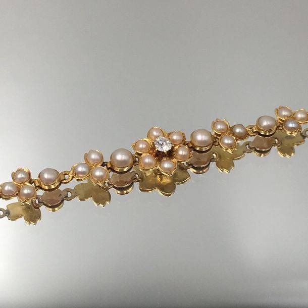BRACELET «fleurs» en or jaune et or rose (750 millièmes), articulé, à maillons rectangulaires, centré de motifs floraux serti d'un diamant taille ancienne et demi-perle