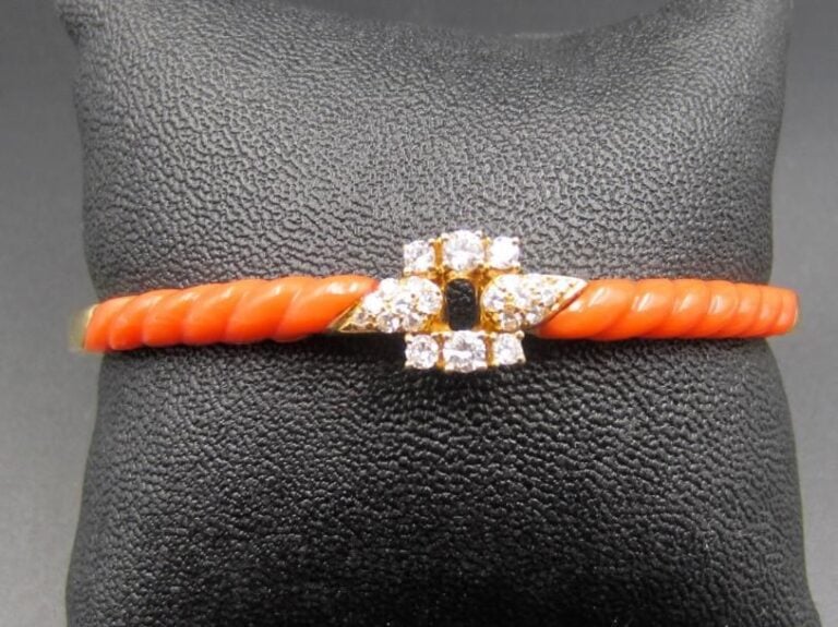 BRACELET jonc rigide ouvrant en or jaune (750 millièmes) ajouré serti de diamants taille brillant épaulé de corail godronné Long : 16,5 cm Poids brut : 21,6 g