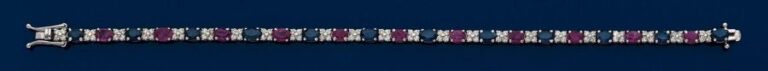 BRACELET ligne en or gris 14 carats (585 millièmes) serti de saphirs et rubis de forme ovale alternés de petits diamants taille brillant à motifs de fleurette
