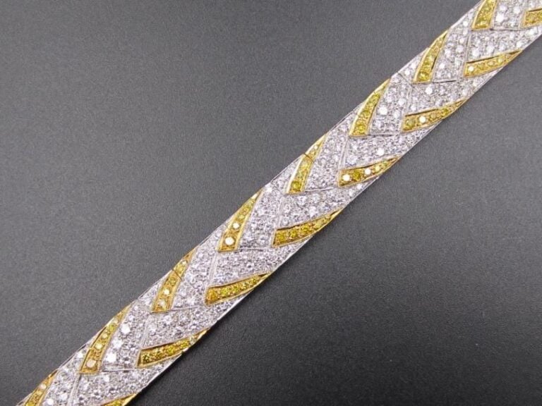 BRACELET MANCHETTE rectangulaire, articulé, en or jaune et or gris (750 millièmes) serti de diamants blancs et jaune à motifs géométrique