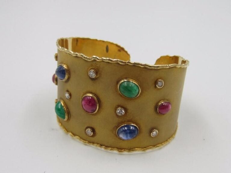 BRACELET manchette rigide ouvert en or jaune (750 millièmes) satiné serti d’émeraudes, saphirs et rubis cabochons de forme ovale et diamants 8/8 en serti clo