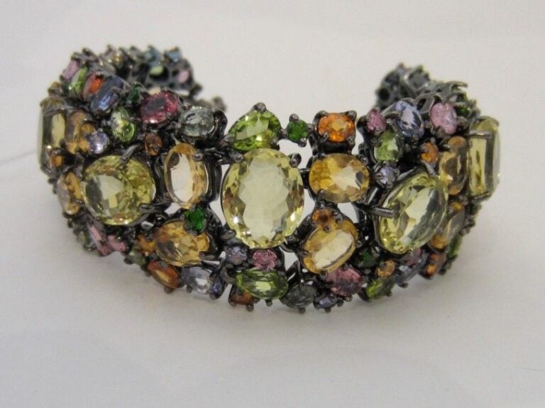 BRACELET MANCHETTE « Tutti frutti » articulé en or jaune (750 millièmes) et argent noirci (925 millièmes) ajouré serti de citrines, péridots, tanzanites, saphirs multicolores et grenats, dont neuf plus important