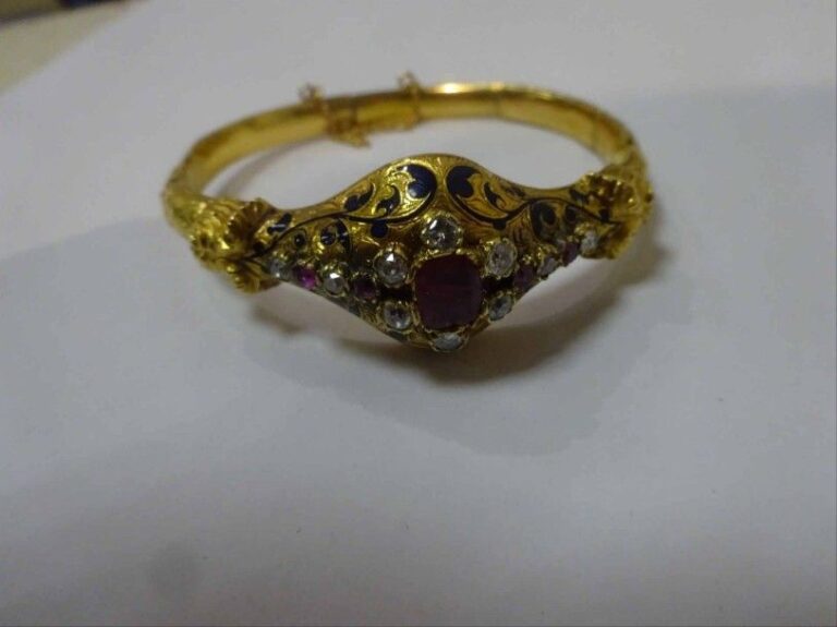 Bracelet rigide et articulé en or jaune 18K (750°/00) ciselé, rehaussé d'un décor floral émaillé, serti d'un rubis central taille coussin, entouré de diamants taille ancienne et de rubi