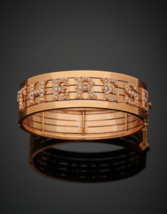 BRACELET rigide ouvrant (750‰) ajouré, flanqué de lettres ornées de demi-perles…