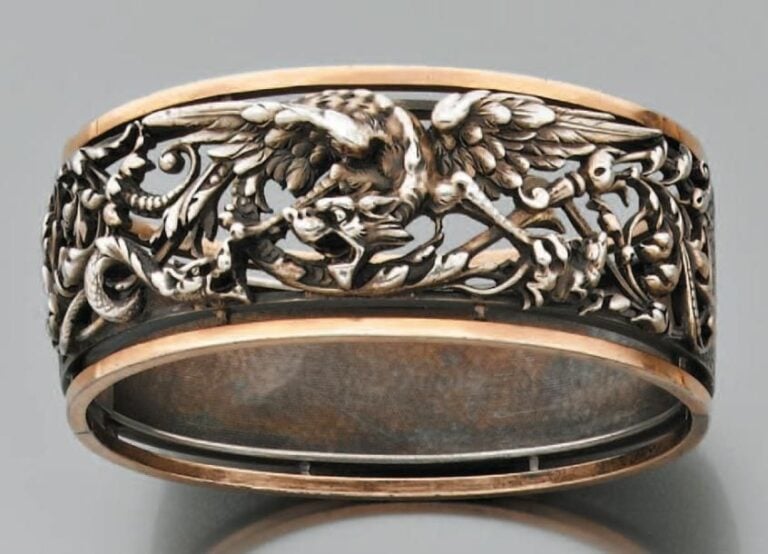 BRACELET rigide ouvrant en or jaune et argent ajourés et ciselés, à un motif de dragon ailé et volute