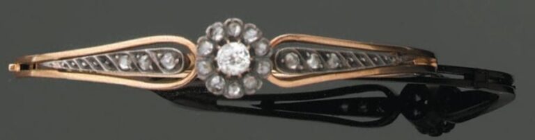 BRACELET rigide ouvrant en or jaune et argent ajourés sertis d'un diamant taille ancienne de forme coussin et de rose