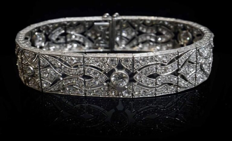 Bracelet ruban articulé en or blanc 18K (750%o) ajouré à décor de méandres sertis de diamants taille ancienne et 8/8, dont les trois plus importants pesant en