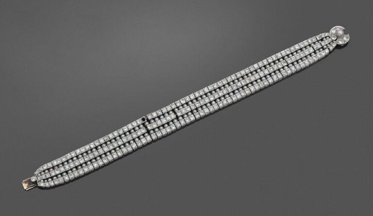 • BRACELET «ruban» en platine (950‰) souple, serti de trois alignements de diamants taille ancienne alternés de deux alignements de perles probablement fines, dont une plus importante sur le fermoi
