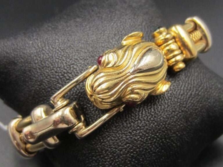 BRACELET semi-rigide «panthère» en or jaune (750 millièmes) godronné et ajouré, rehaussé de pierres vertes et rouges cabochon