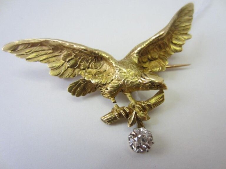 BROCHE «aigle aux ailes déployées» en or jaune (750 millièmes) ciselé et sculpté retenant en pampille un diamant taille ancienn