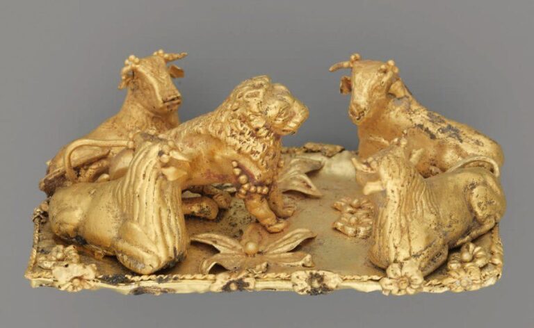 BROCHE AUX ANIMAUX Plaque rectangulaire, décorée de rosettes et fleurs écloses et garnie dans les angles de quatre figurines de taureaux couchés, tête tournée en direction d'un lion accroup