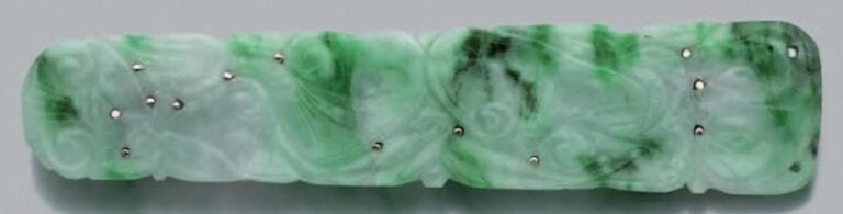 BROCHE BARRETTE en or gris serti d'une plaque rectangulaire en jade sculpté, gravé et repercé, à décor de feuille stylisé