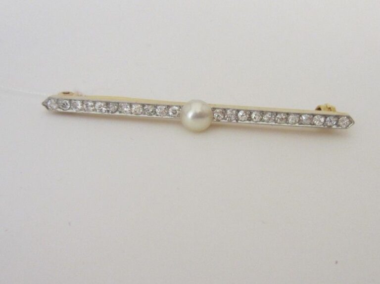 BROCHE barrette en platine (850 millièmes) et or jaune (750 millièmes) orné d'une perle de culture blanche légèrement bouton, épaulée d'un alignement de diamants taille ancienn