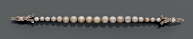BROCHE barrette en platine (900 millièmes) et or jaune 14 carats (585 millièmes) orné d'un alignement de perles probablement fines (non testées), de forme bouton, en chut