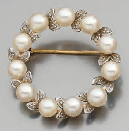 BROCHE circulaire en or jaune et or gris sertis de perles de culture blanches alternées de diamants tailles en ros