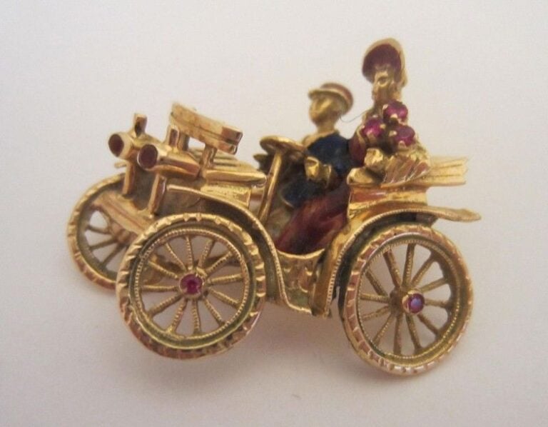 Broche "couple dans une voiture ancienne" en or jaune (750 millièmes), partiellement émaillé et serti de pierres rouge