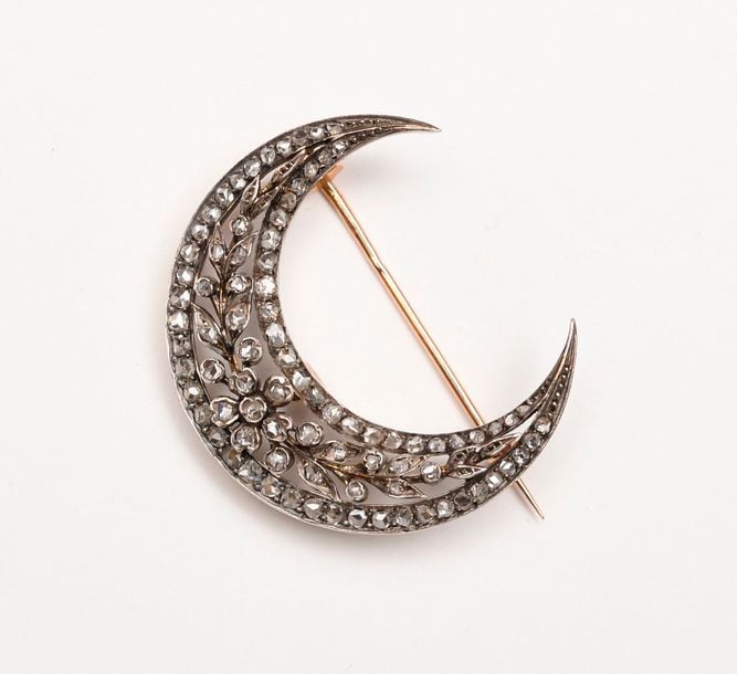 BROCHE croissant en or jaune et argent ajourée à décor de fleur et feuillage entouré de diamants taillés en ros