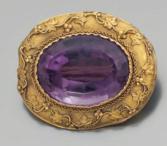 BROCHE de forme ovale en or jaune amati et ciselé à motifs de pampres retenant en son centre une importante améthyst