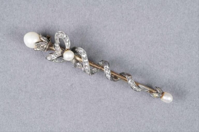 Broche en argent (925%o) et en or jaune 18K (750%o) à motif d'un noeud enroulé, sertie de diamants taille rose et de perles fines et perle bouto