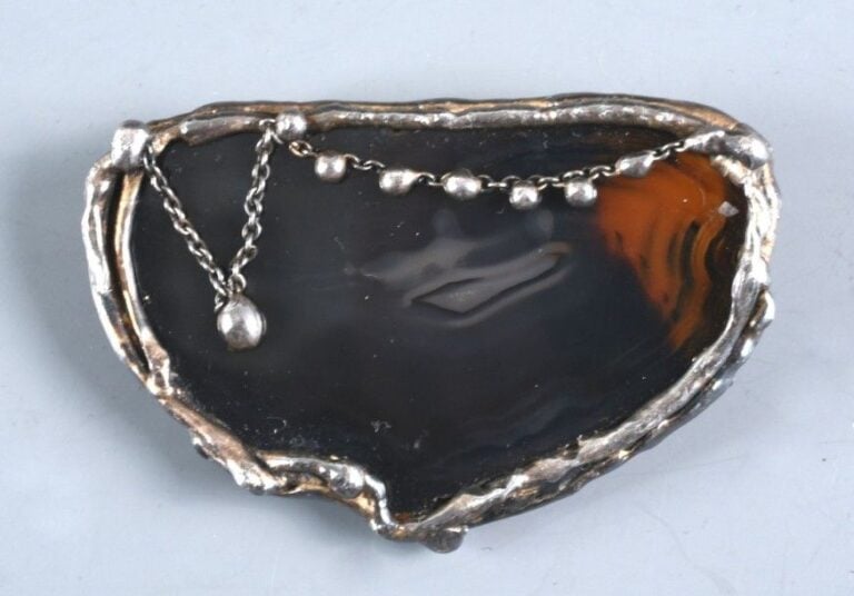 Broche en métal blanc sertie d'une agate rehaussé d'une chaînette en pendan