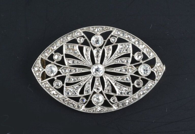 Broche en or blanc 18k (750°/00) en forme de mandorle ajourée, sertie de diamants taille rose et de cinq diamants taille ancienne en