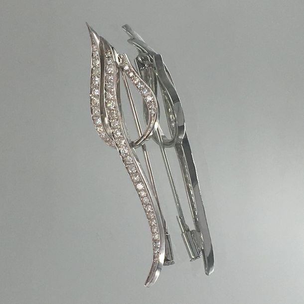 BROCHE en or gris (750 millièmes) ajouré, à motifs de volutes, serti d'alignement de diamant