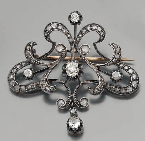 BROCHE en or jaune et argent ajouré serti de diamants taille ancienne et de roses, retenant deux diamants en pampill