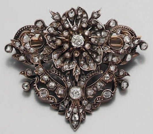 BROCHE en or rose et argent ajouré serti de diamants taille ancienne et de roses, à motifs de fleur et volute