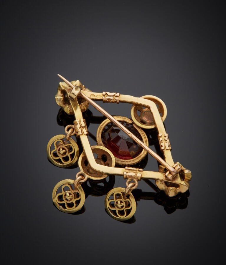 BROCHE losangique en or jaune (750‰) ajouré, ciselé, serti de huit grenats pyro…
