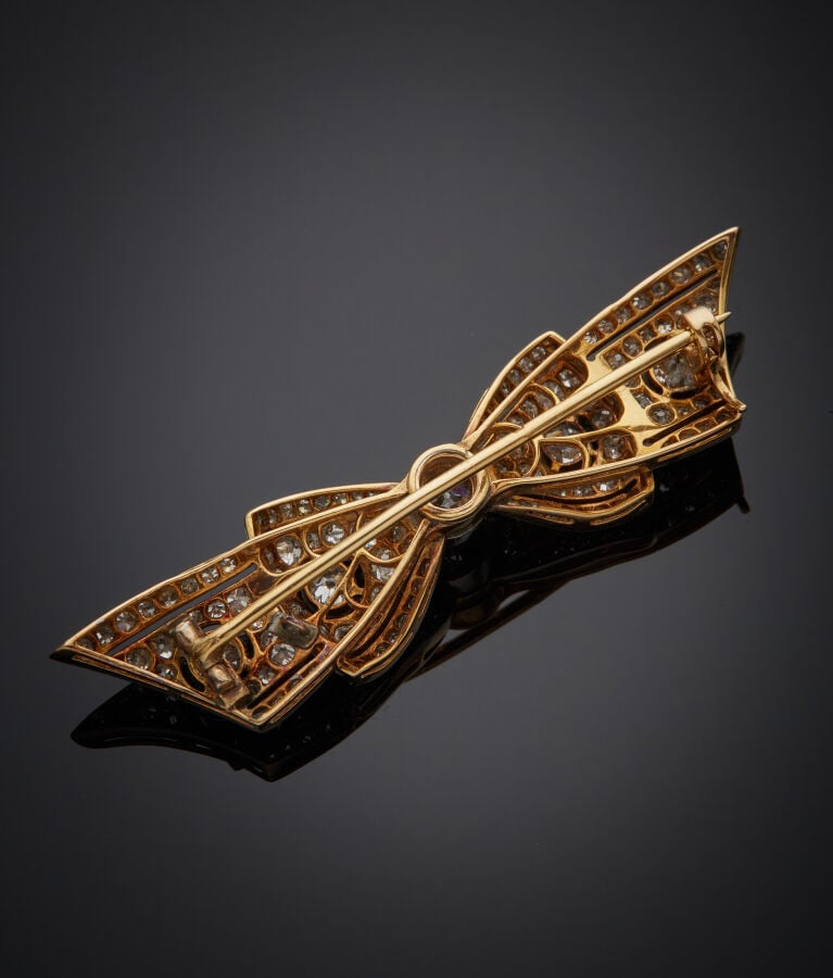 BROCHE "noeud" en or jaune et or gris (750‰) finement ajouré, serti de diamants…