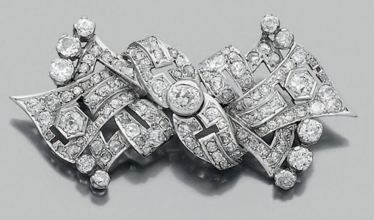 BROCHE «noeud» stylisé en platine (950 millièmes) et or gris (750 millièmes) ajouré, serti de diamants taille ancienne, certains plus important