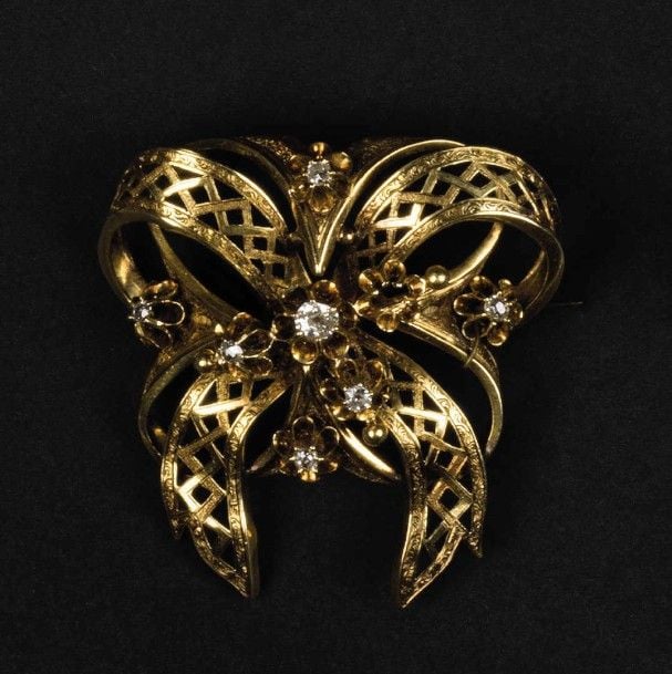 Broche noud en or jaune 18K (750°/00) ciselé et ajouré serti de diamants de taille ancienne