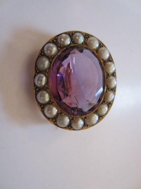 BROCHE ovale en or rose ajouré serti d'une importante améthyste entourée de demi-perles probablement fine
