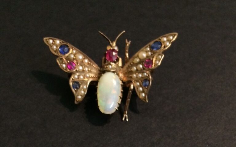 BROCHE «papillon» articulée en or rose (375 millièmes) 9 carats serti d'une opale de forme ovale, de demies perles, pierres rouges et bleue