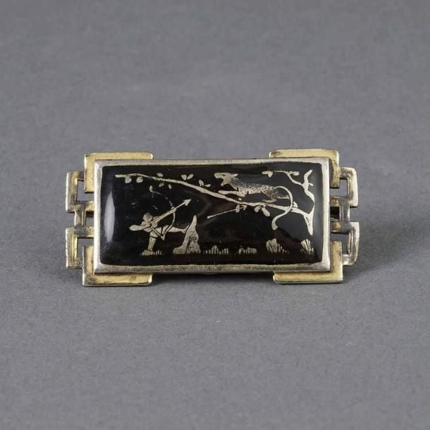 Broche rectangulaire en métal doré à décor de grecques rehaussées d'une scène émaillée noire et dorée figurant une chasse au léopar