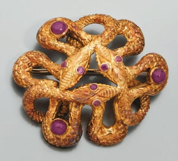 BROCHE «trois serpents» en or jaune entièrement ciselé et ajouré, serti de rubis ronds et cabochon